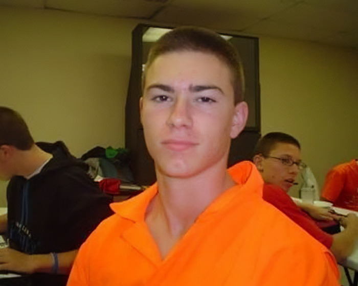 Young man in an orange shirt representing mom's claim that skinned body in Las Vegas museum is her son, sparking online debate.