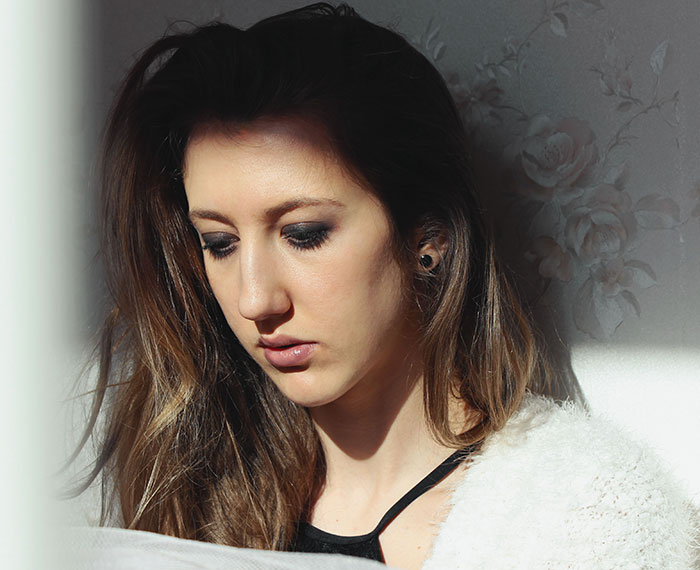 Sad woman with long hair looking down, reflecting on what SIL thinks about her on Thanksgiving.