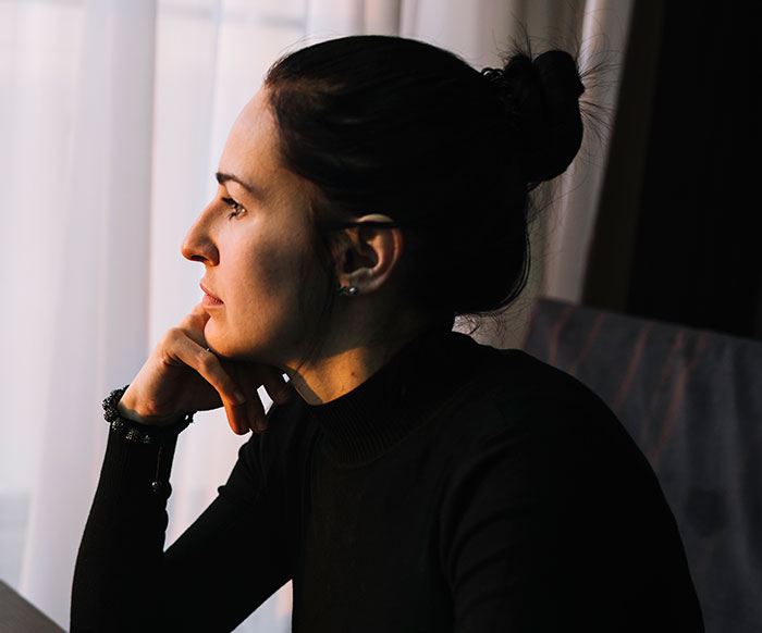 Woman in black turtleneck looking thoughtful and sad, reflecting on what sister-in-law thinks on Thanksgiving.