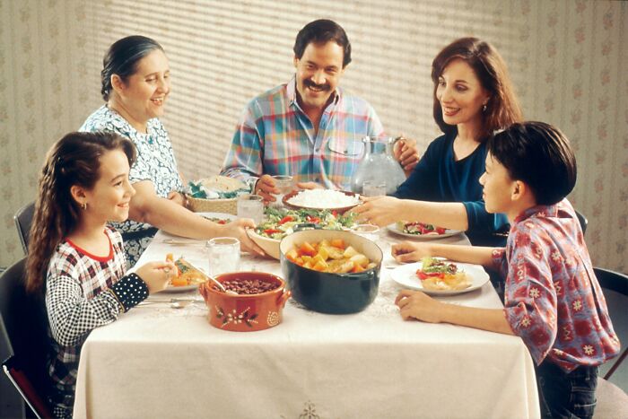 Family of five sharing a meal at a dining table, illustrating childhood habits and family interactions.