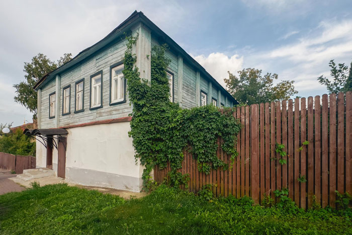 Old wooden house beside a wooden fence covered with greenery, illustrating a neighbor replacing a rotten fence dispute. Old wooden house beside a wooden fence covered with greenery, illustrating a neighbor replacing a rotten fence dispute.