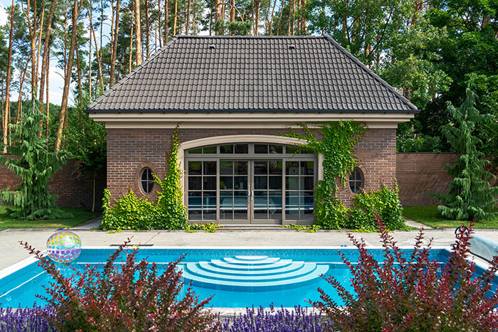 Backyard pool and brick house surrounded by trees in a neighbor’s yard where kids used without asking. Backyard pool and brick house surrounded by trees in a neighbor’s yard where kids used without asking.