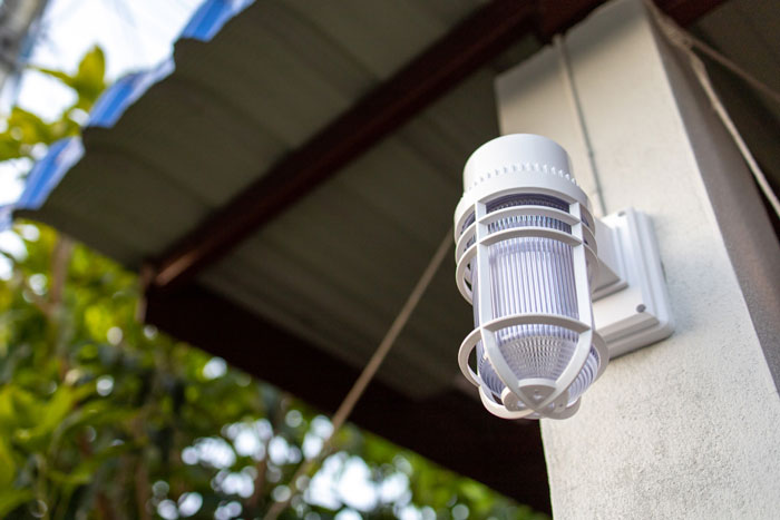 Outdoor solar light installed on a house exterior with trees in the background during daylight sunlight. Outdoor solar light installed on a house exterior with trees in the background during daylight sunlight.
