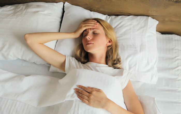 Woman resting in bed with eyes closed and hand on forehead, illustrating effects of neighbours installed actual sun exposure. Woman resting in bed with eyes closed and hand on forehead, illustrating effects of neighbours installed actual sun exposure.