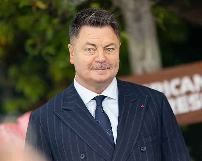 Nick Offerman in a pinstripe suit outdoors, linked to X-rated comment during live broadcast causing host apologies.