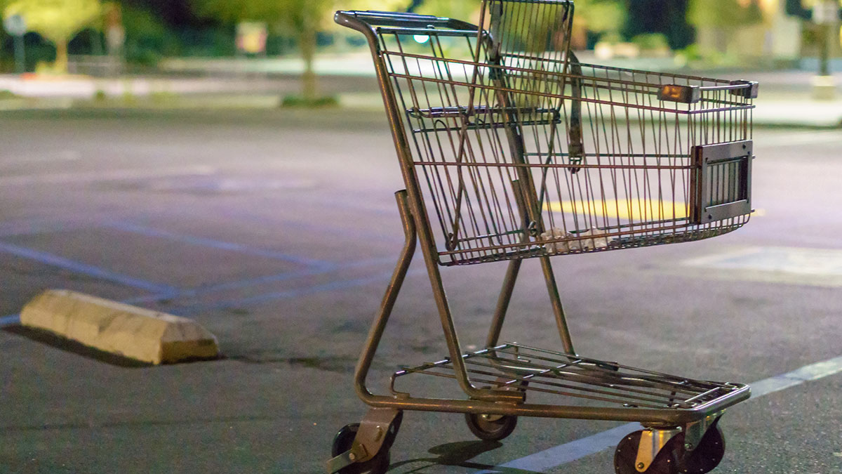 Empty shopping cart in a dimly lit parking lot representing gas station workers sharing their wild stories.