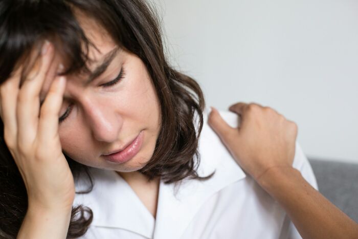 Young woman with anxious expression being comforted, representing the emotional impact of surveillance cameras nightmare fuel.