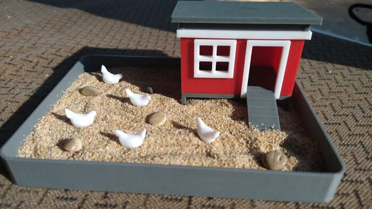 Miniature novelty item featuring a small red house and sand with tiny white bird figures in a tray.