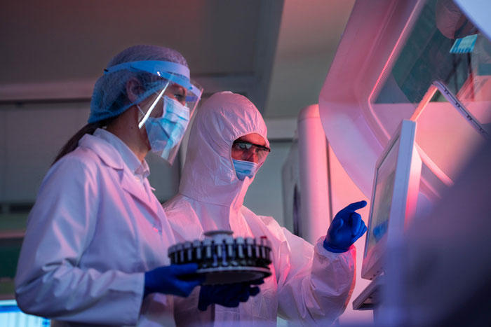 Two lab workers in protective gear operating equipment, illustrating office shutdown due to strict by the book policies. Two lab workers in protective gear operating equipment, illustrating office shutdown due to strict by the book policies.