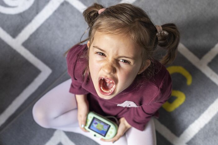 Young girl having a tantrum while sitting on the floor, showing daily screaming and meltdowns that take a toll on family. Young girl having a tantrum while sitting on the floor, showing daily screaming and meltdowns that take a toll on family.