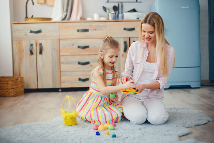 Woman and young child play on floor in kitchen, highlighting challenges of daily screaming and meltdowns with 3-year-old toddler. Woman and young child play on floor in kitchen, highlighting challenges of daily screaming and meltdowns with 3-year-old toddler.
