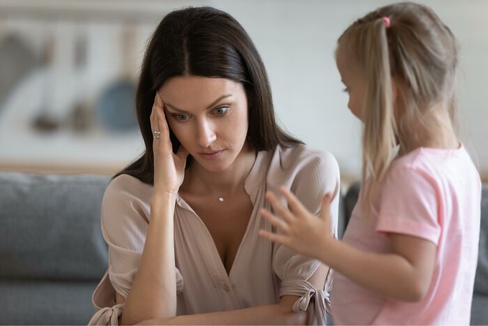 Stressed woman coping with daily screaming and meltdowns from her 3-year-old child at home on couch. Stressed woman coping with daily screaming and meltdowns from her 3-year-old child at home on couch.