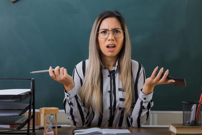 Teacher looking confused and frustrated in a classroom setting, reflecting an autistic teen punished for not reading sarcasm.