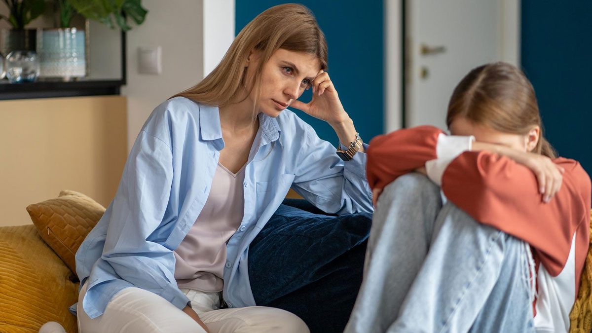 Worried mother comforting autistic teen who is upset after being punished by teacher for not reading sarcasm.