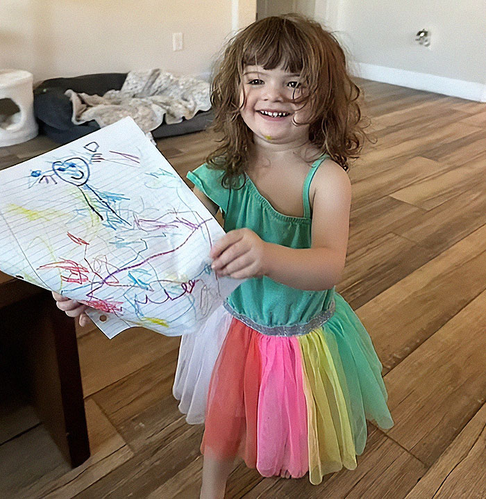 Toddler girl in colorful dress holding crayon drawing indoors relating to story of dad leaving 2YO in car during adult video binge. Toddler girl in colorful dress holding crayon drawing indoors relating to story of dad leaving 2YO in car during adult video binge.
