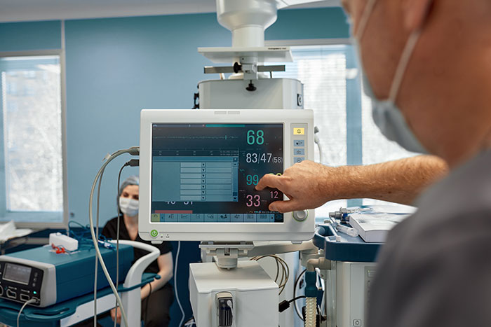 Medical professional checking vital signs on monitor in hospital room with a patient, related to coma survivors’ stories.