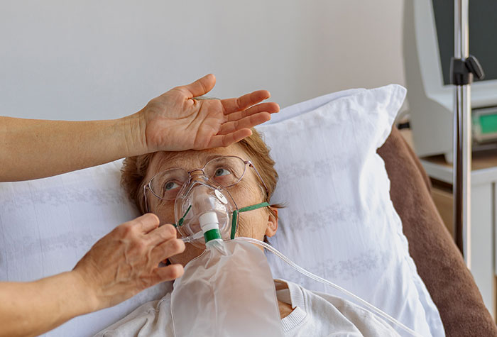 Elderly woman in hospital bed receiving oxygen, illustrating coma survivors sharing their recovery stories.