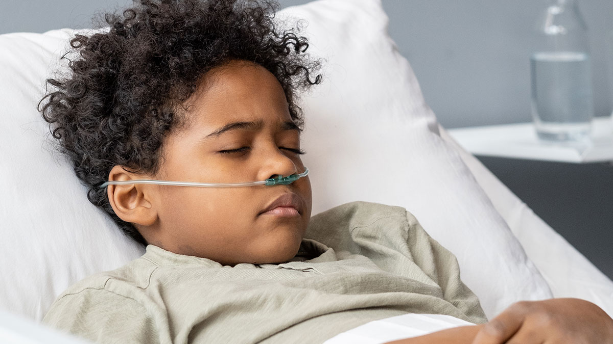 Young patient with nasal oxygen tube lying in hospital bed, representing coma survivors sharing their stories.