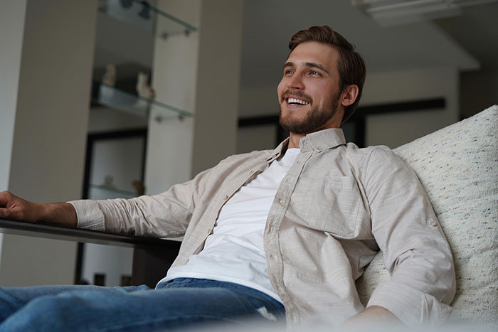 Smiling young man relaxing at home, representing people who walked away from their old lives and started a new one.