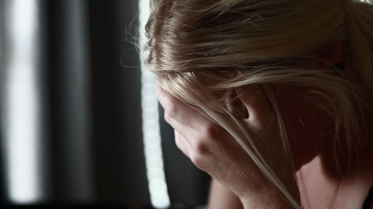 Woman with blonde hair covering her face in frustration, illustrating people's dissatisfaction with HOA dumb rules.