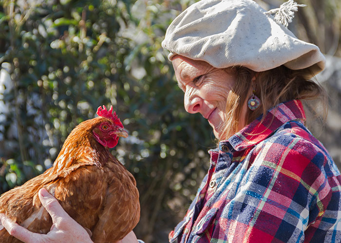 Woman holding a chicken outdoors, showcasing one of the most intelligent pets people have ever had.