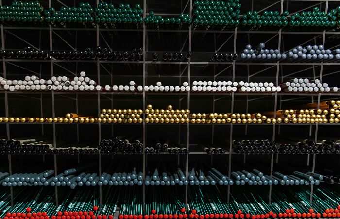 Rows of colored drumsticks arranged by color in a grid rack, challenging viewers to spot the connection. Rows of colored drumsticks arranged by color in a grid rack, challenging viewers to spot the connection.
