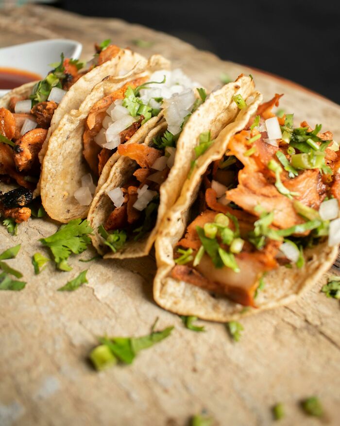Close-up of tacos filled with seasoned meat, onions, and fresh cilantro on a rustic surface for heavy confessions feature.