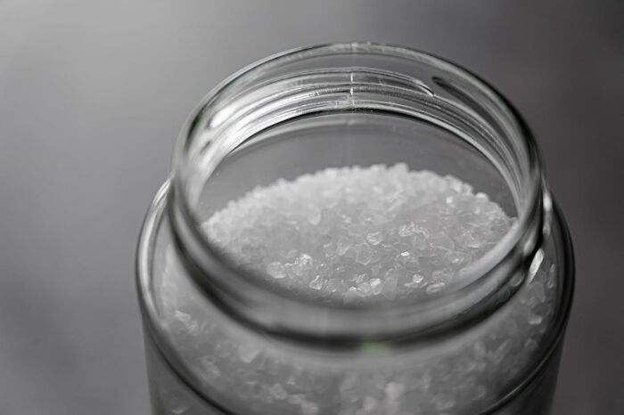 Close-up of coarse sea salt in a glass jar, highlighting kitchen essentials for home cooks to sharpen their knives correctly.