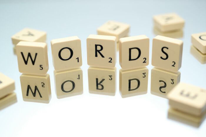 Scrabble tiles spelling words reflected on a smooth surface, illustrating everyday words and their language roots. Scrabble tiles spelling words reflected on a smooth surface, illustrating everyday words and their language roots.