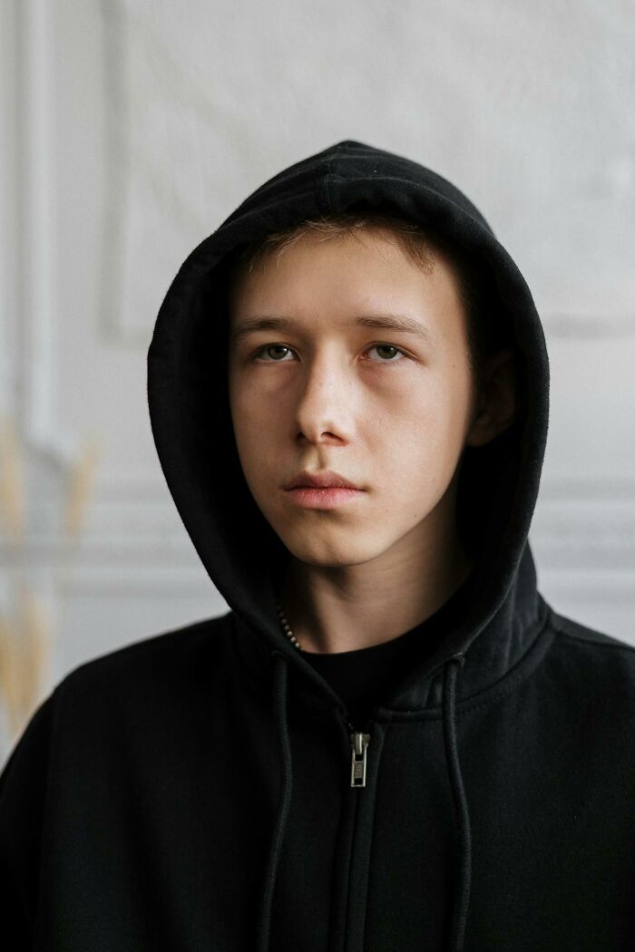Teen boy in black hoodie with serious expression, illustrating funny and serious moments parents realized they were raising monsters.