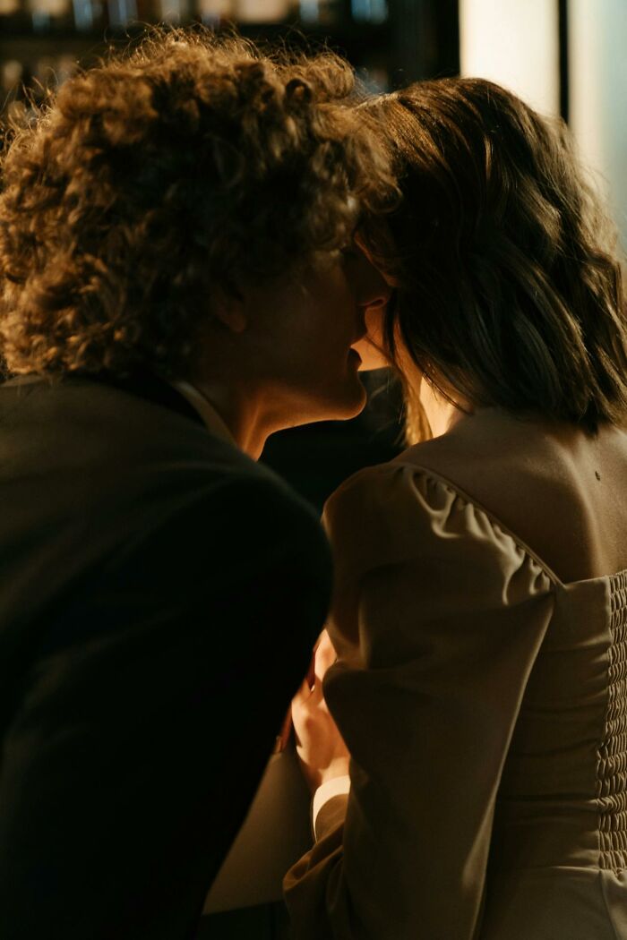 Two people whispering closely in a dimly lit setting, hinting at heavy confessions nobody was charged with.