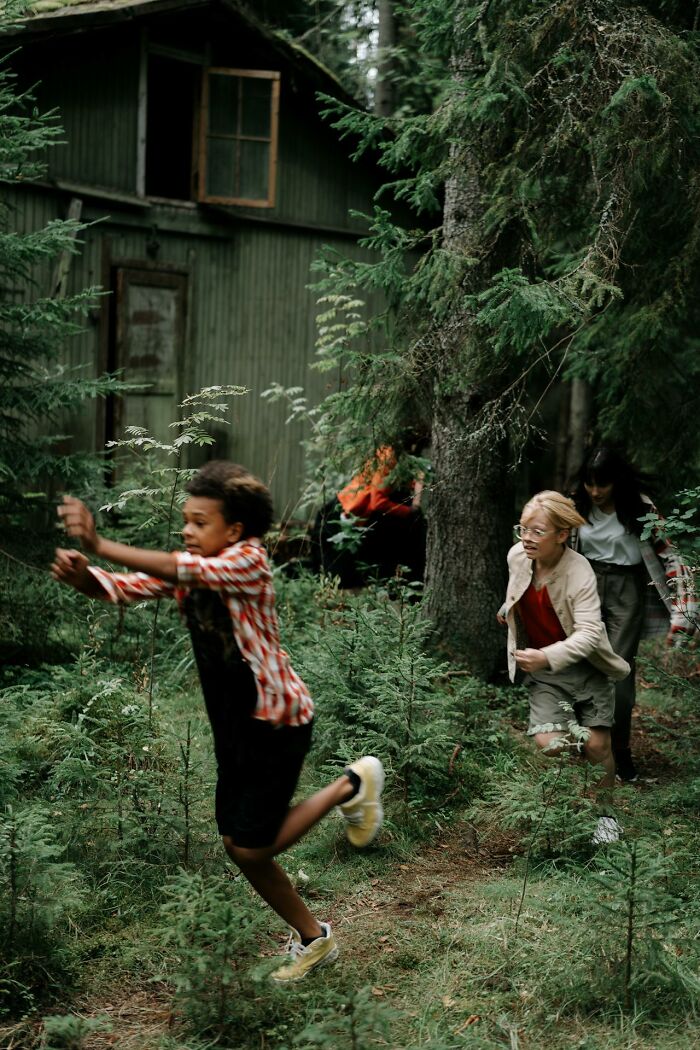 Children running through dense forest near old cabin, capturing a creepy and bizarre scene witnessed by park rangers and hikers.