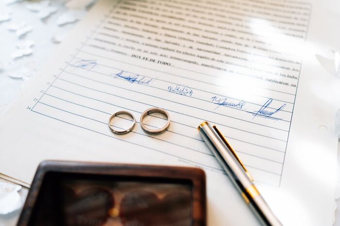 Two wedding rings on a signed document with a pen nearby, symbolizing harsh truths about marriage realities.