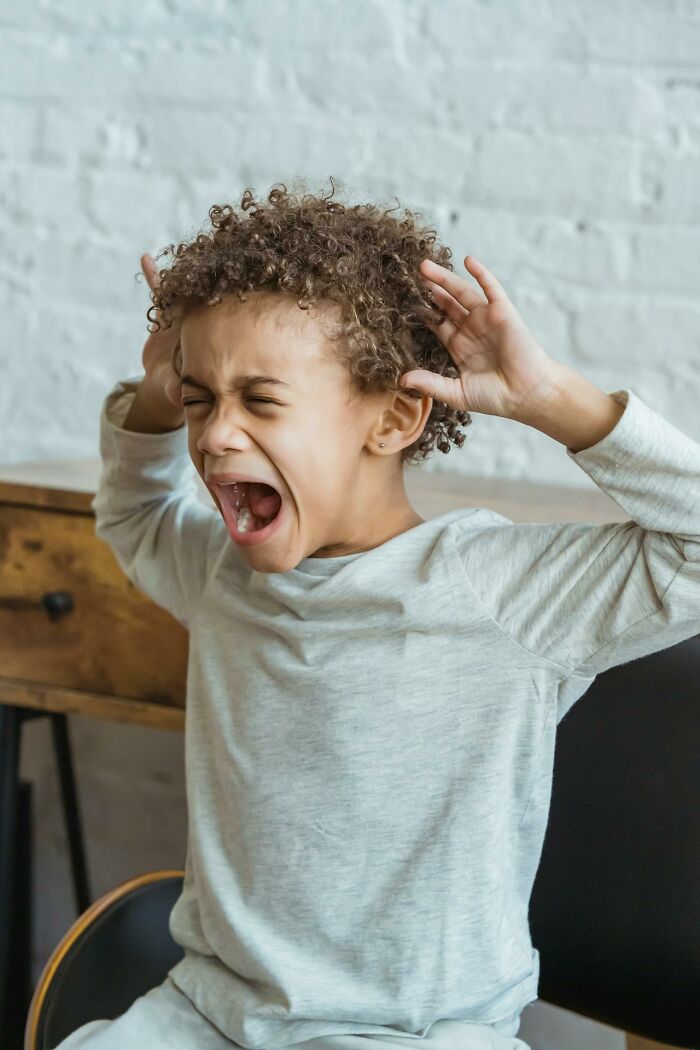 Child in a light gray shirt screaming with hands raised, representing intense emotions in psych ward nurse stories.
