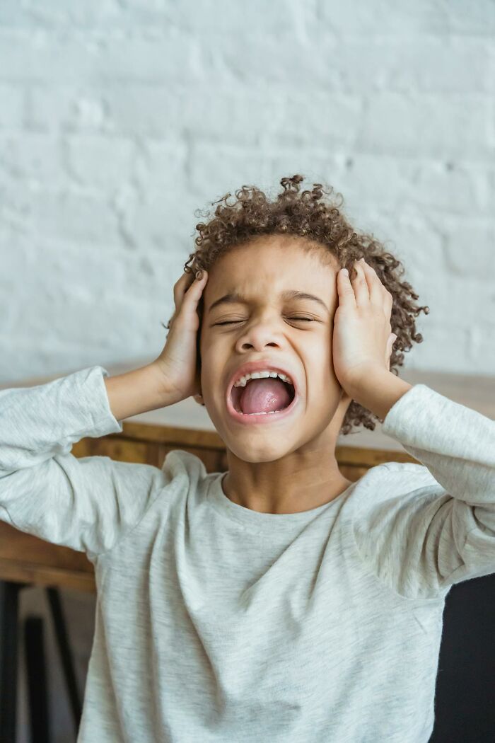 Young child screaming and holding head in frustration, capturing funny and serious moments parents realized they were raising monsters.