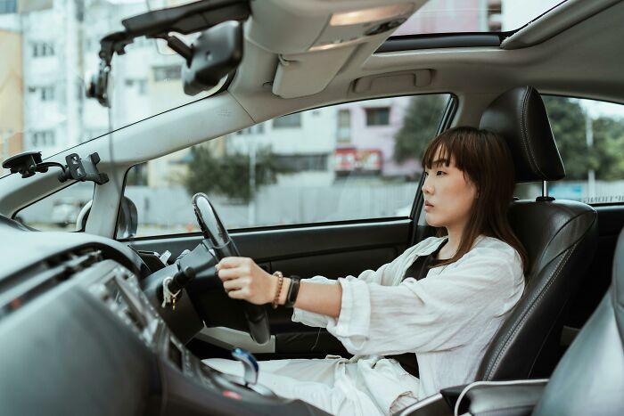 Woman sitting in the driver's seat of a car, relatable moment showing one of the ridiculous but common things people do.