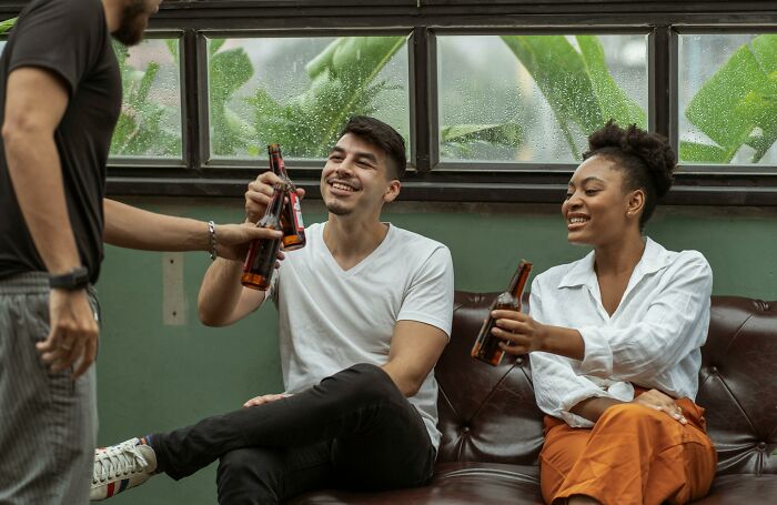 Three friends sharing drinks and laughing together, capturing relatable and ridiculous social moments.