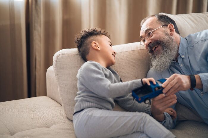 Young boy and elderly man sharing a joyful moment playing with a toy car, capturing bizarre moments of connection.
