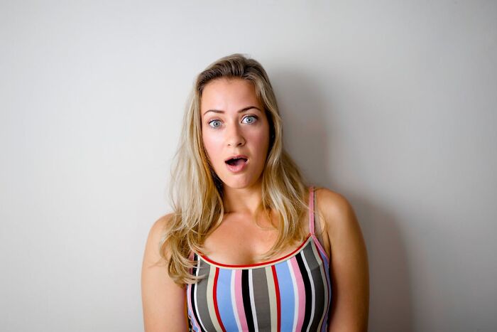 Shocked woman with long blonde hair and striped tank top showing surprise in funny and serious parent moments raising monsters.