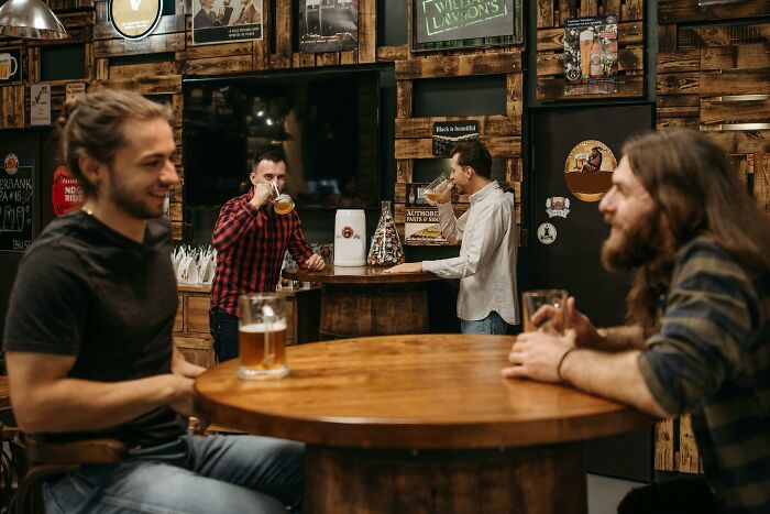 Men enjoying drinks at a rustic bar, relatable moments of socializing and having fun with friends.