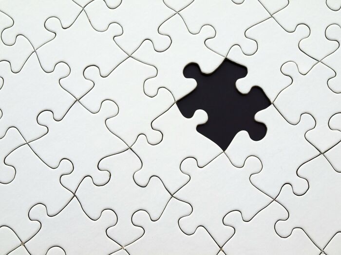 Close-up of a white jigsaw puzzle with one missing piece, symbolizing general knowledge brain teasers.