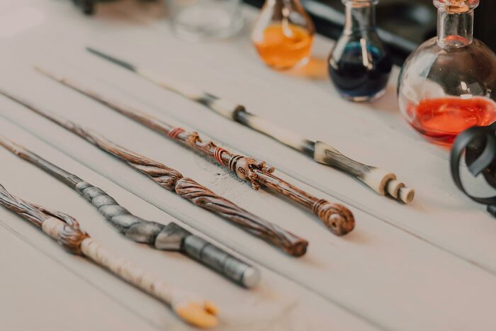 Collection of iconic movie props including intricately designed wands displayed on a table with glass potion bottles.