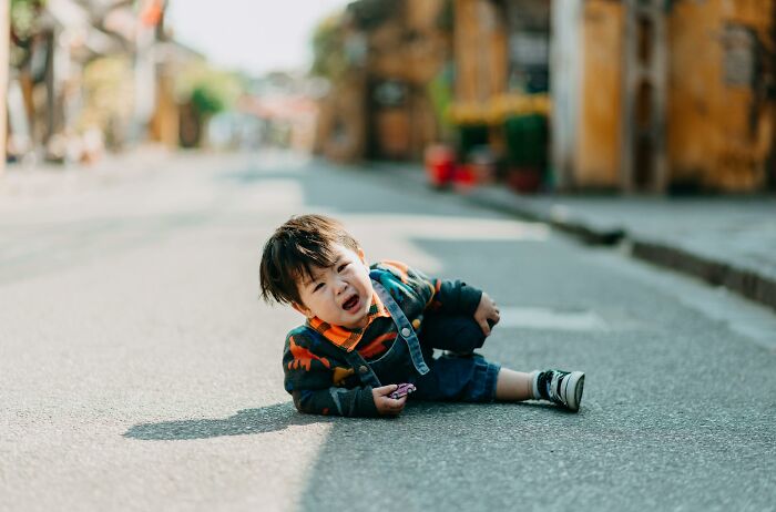 Young child lying on street crying after fall, illustrating real-life horror story moments of fear and distress outdoors.