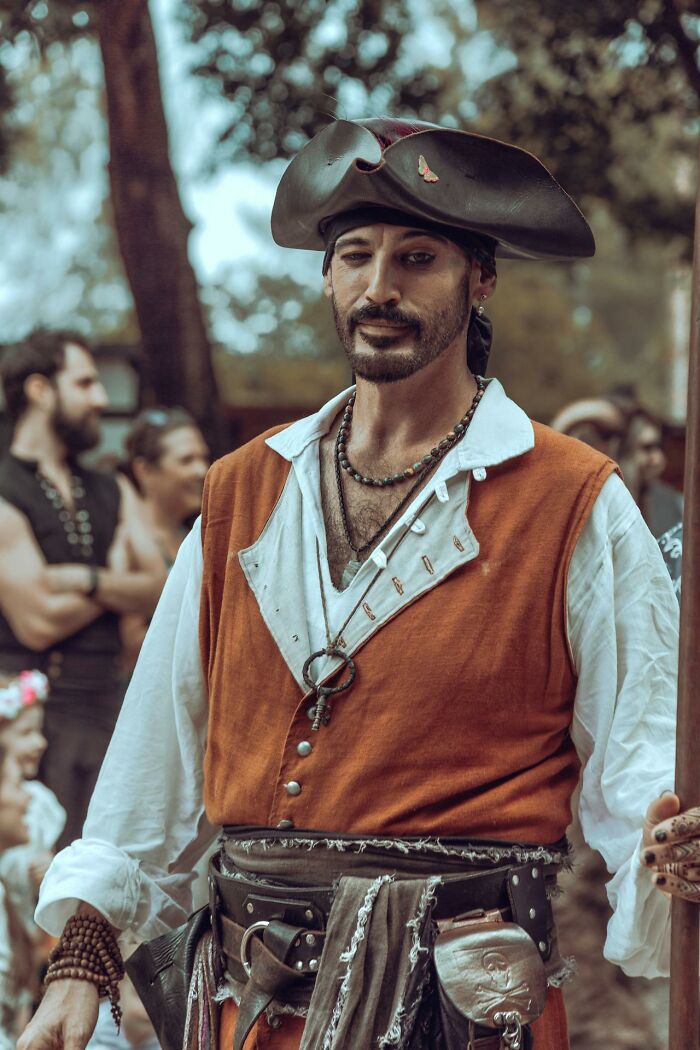 Man dressed as a pirate at a festival among people, capturing one of the bizarre moments that make others wonder about sanity.