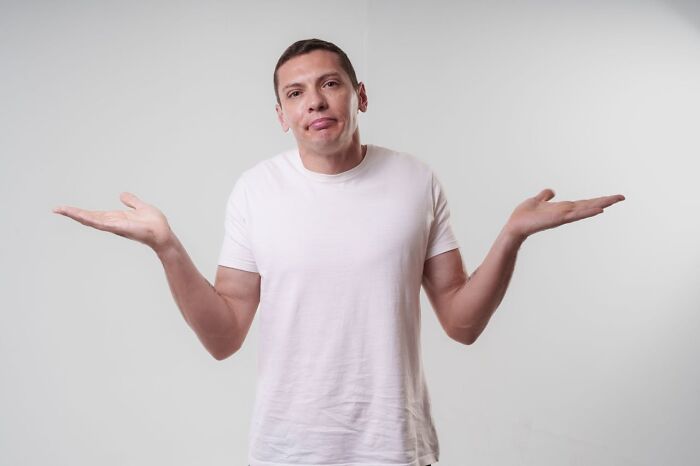 Man in a white t-shirt shrugging with a confused expression, illustrating bizarre moments and sane reactions.