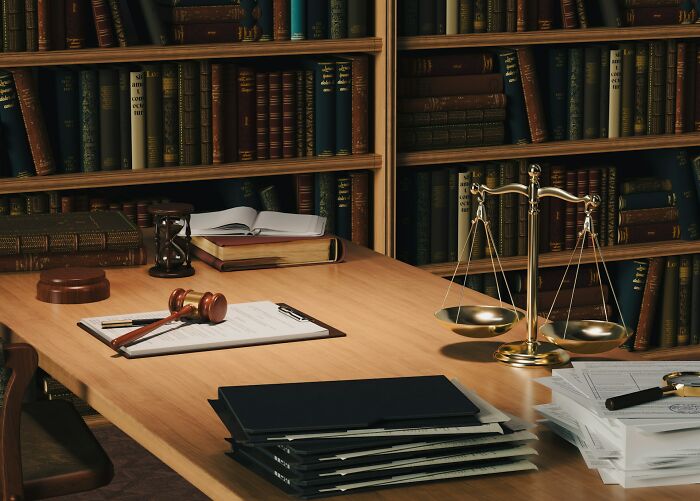 Law office desk with gavel, scale of justice, legal files, and books representing work secrets of professionals like doctors and plumbers.