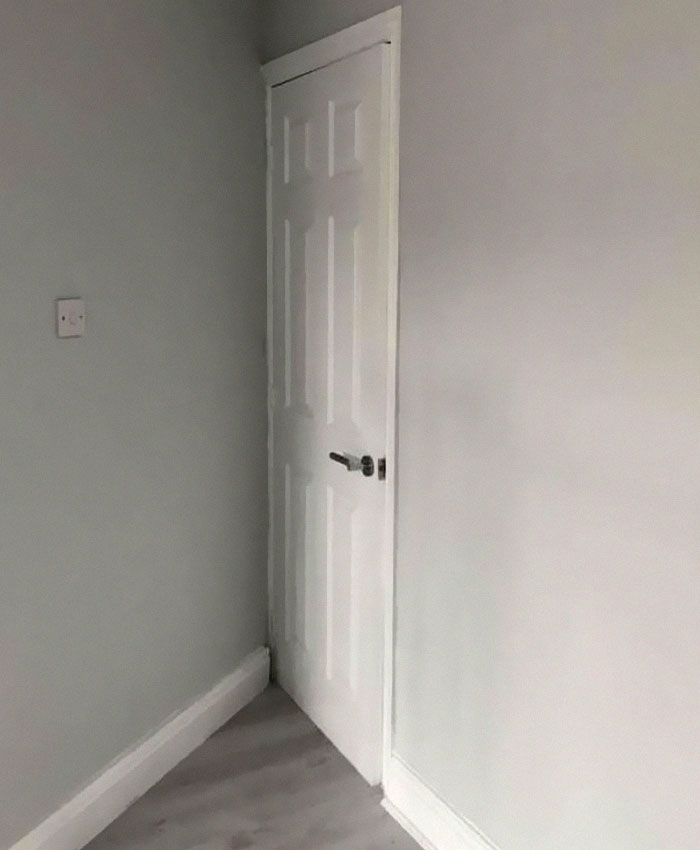 Door installed in a narrow corner with limited space, illustrating a design and architecture nightmare lacking common sense.