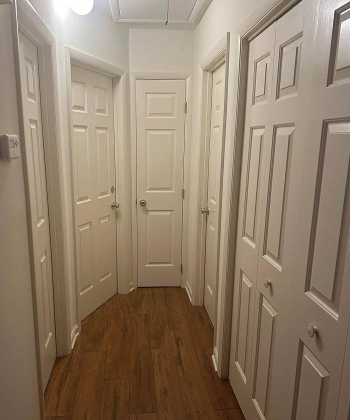 Narrow hallway with multiple white doors close together showing a design and architecture nightmare lack of common sense.