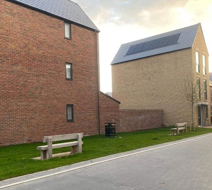 Two benches facing brick walls with no view in a design and architecture nightmare showing lack of common sense.