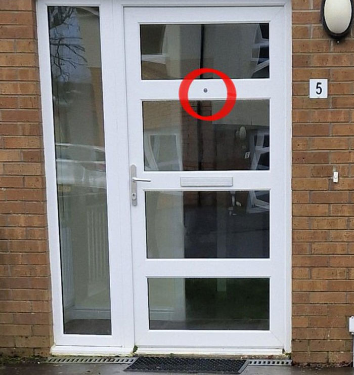 White door with glass panels featuring a peephole placed in the middle panel, showcasing design and architecture nightmares.